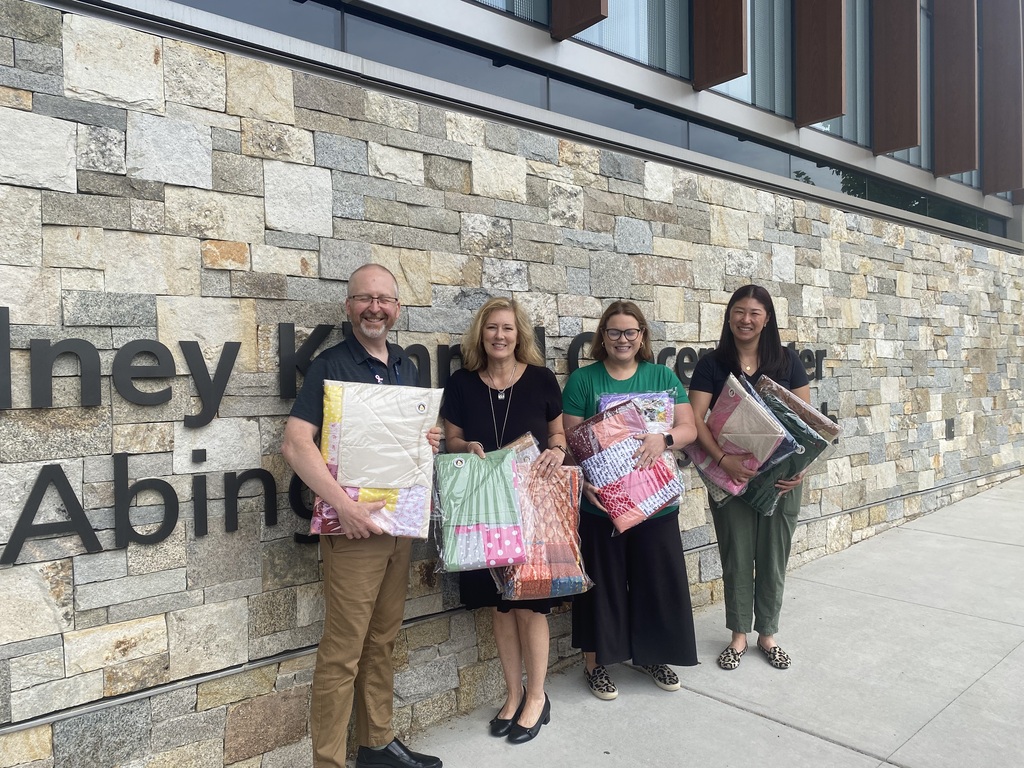 Representatives of the Asplundh Cancer Center hold up the donated quilts in gratitude