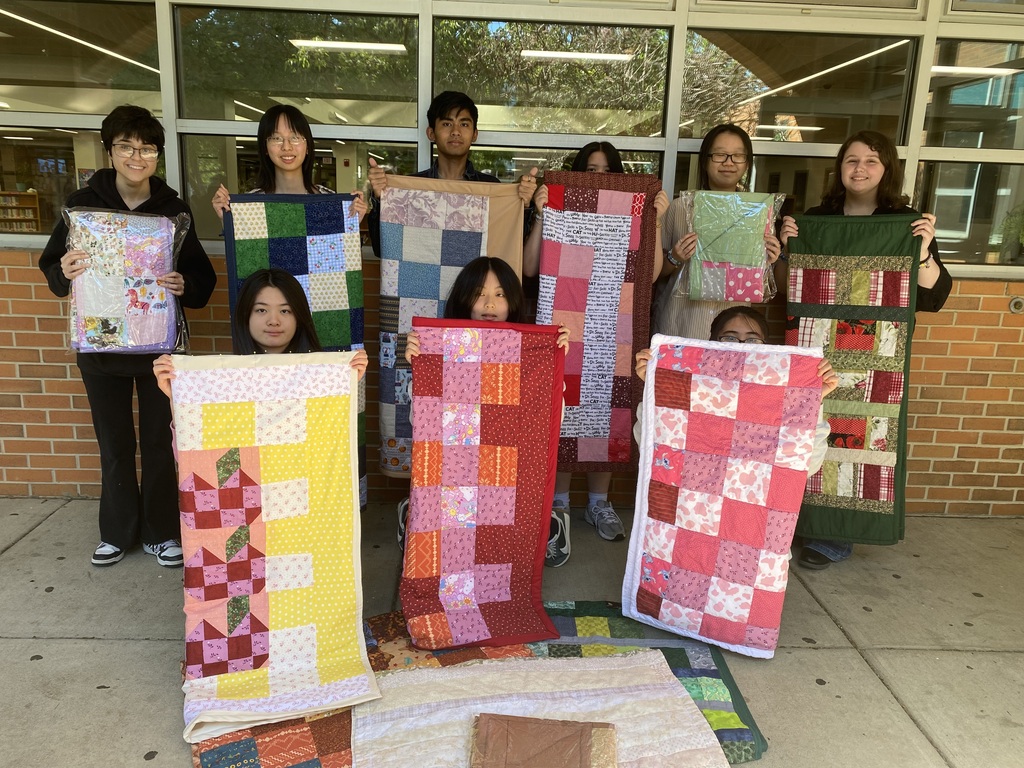 Students from theQuilting Club hold up the quilts they created and donated to Asplundh Cancer Center