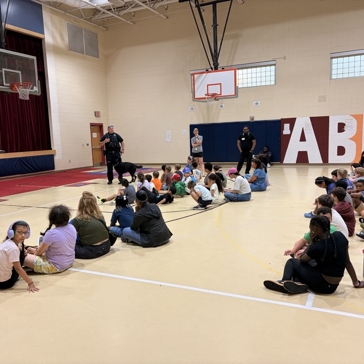 Officer Jones and Shadow talk to a gymnasium of students