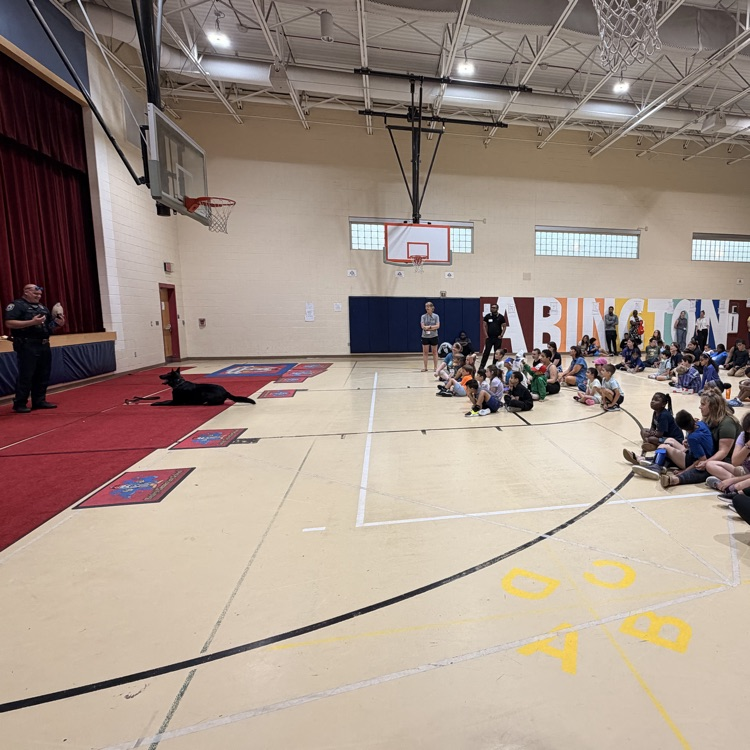 Officer Jones and Shadow talk to a gymnasium of students