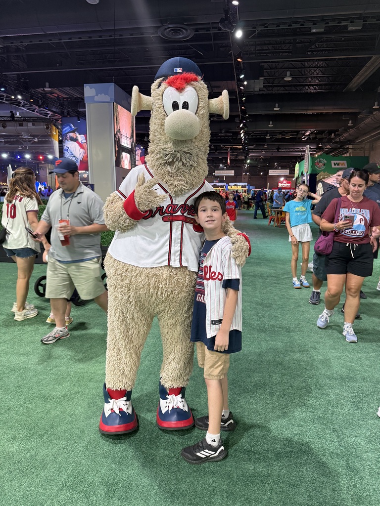 Daniel poses with one of major league baseball's mascots, with other fans in the background