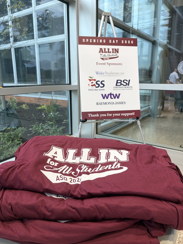 All in for All Students Tshirt with sponsorship poster in the background