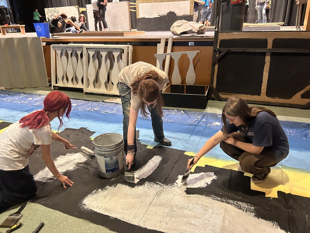Students in the Crew paint sets on stage for the fall play
