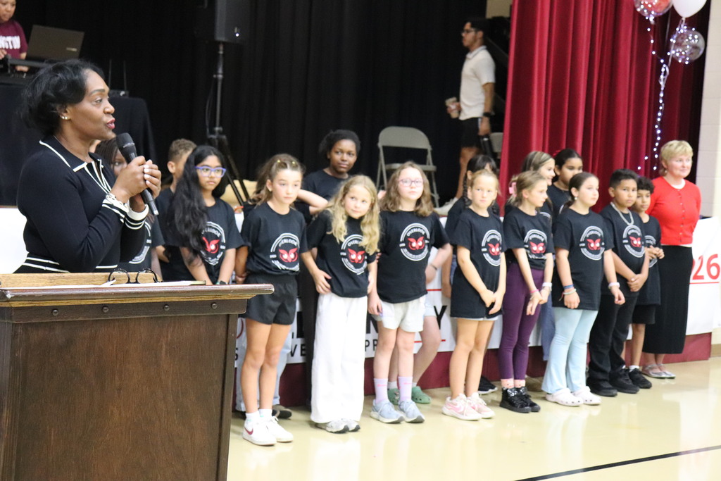 Principal Dr. Karima Boyd addresses attendees with students in the background