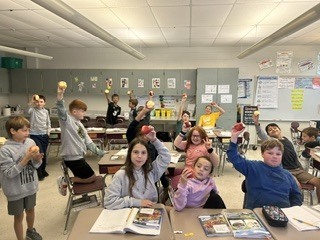 Students smiling and holding up freshly picked apples