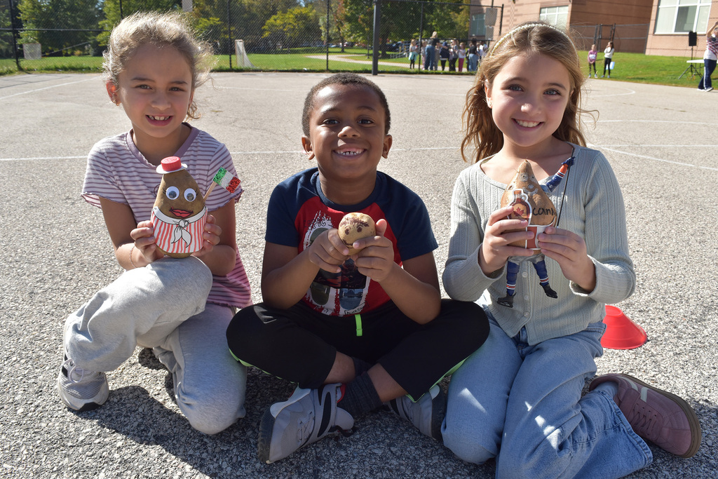 3 second graders smile and pose with their potato athletes