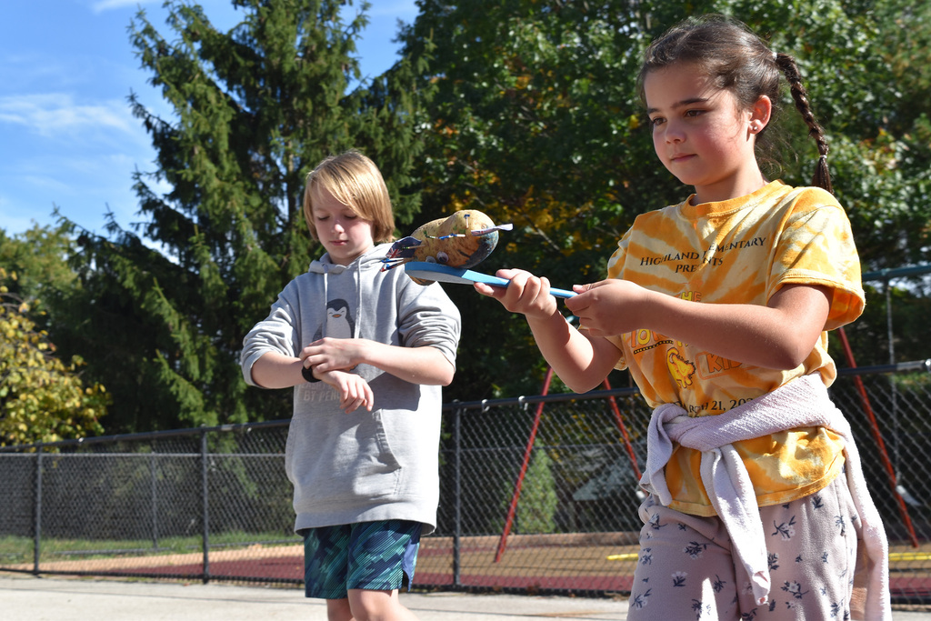 A second grade student is timed as she balances her potato in a competition
