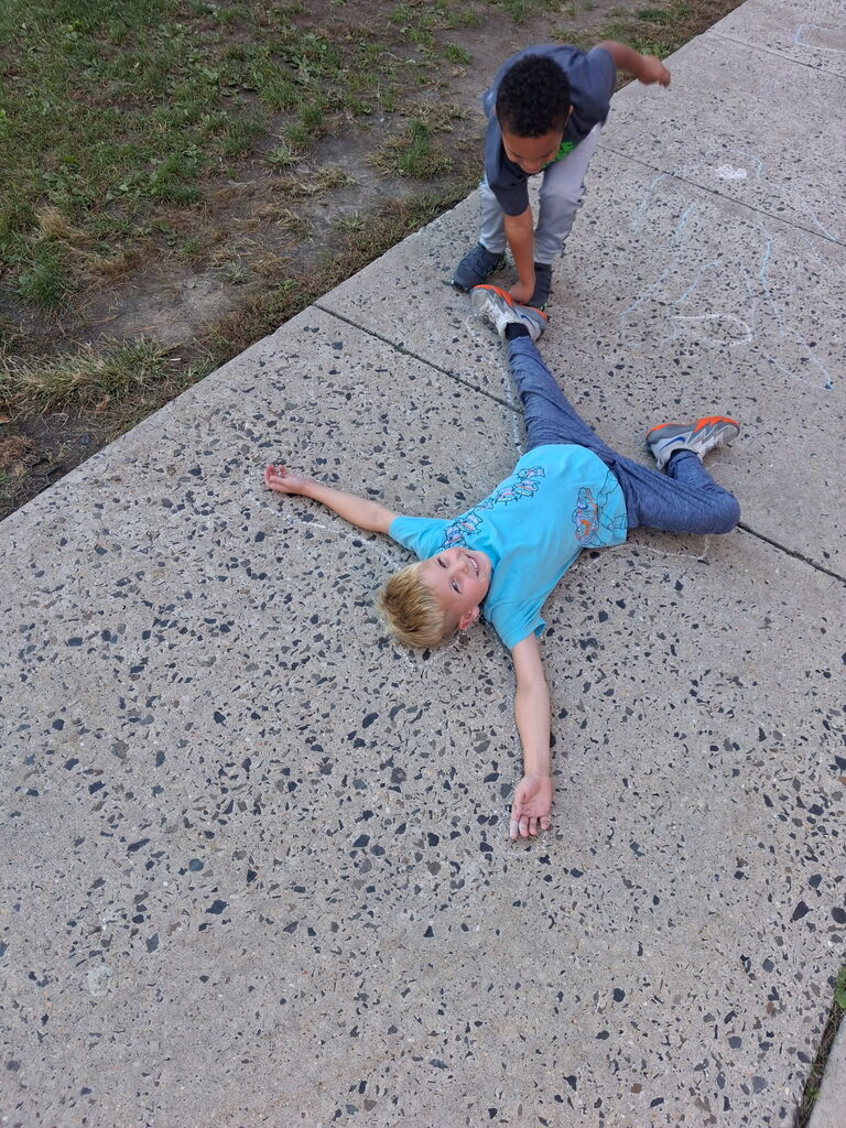 Students chalk outlining their bodies