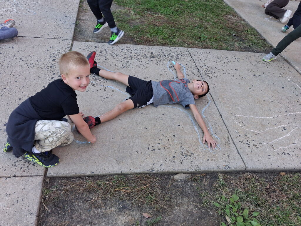Students chalk outlining their bodies