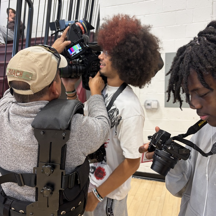 The camera person lets the student photographers hold the camera