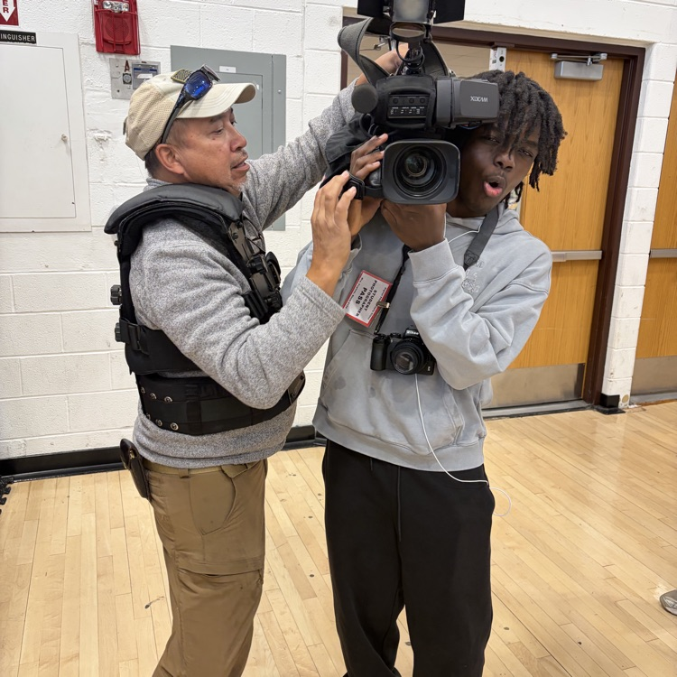 The camera person lets the student photographers hold the camera