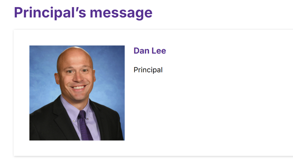 Headshot of bald man in black suit with a dark purple tie smiling