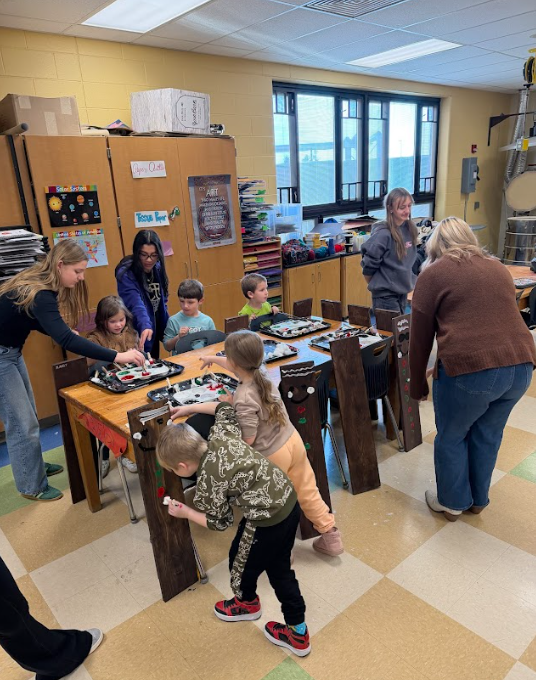 High school students helping kindergarteners with Wood stained gingerbread men decorations