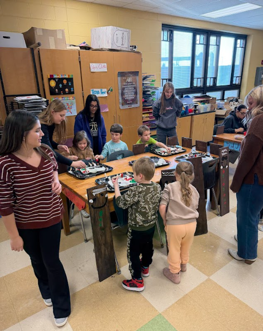 High school students helping kindergarteners with Wood stained gingerbread men decorations