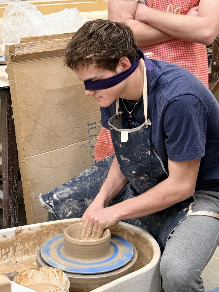 Blindfolded students throwing on a pottery wheel