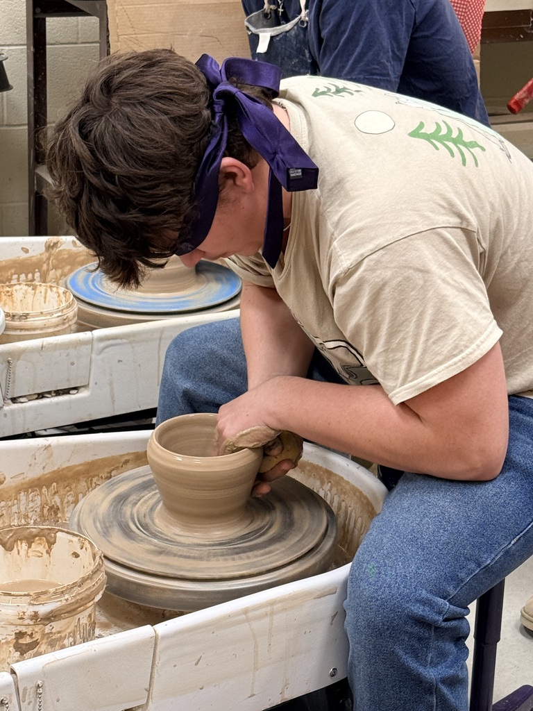 Blindfolded students throwing on a pottery wheel