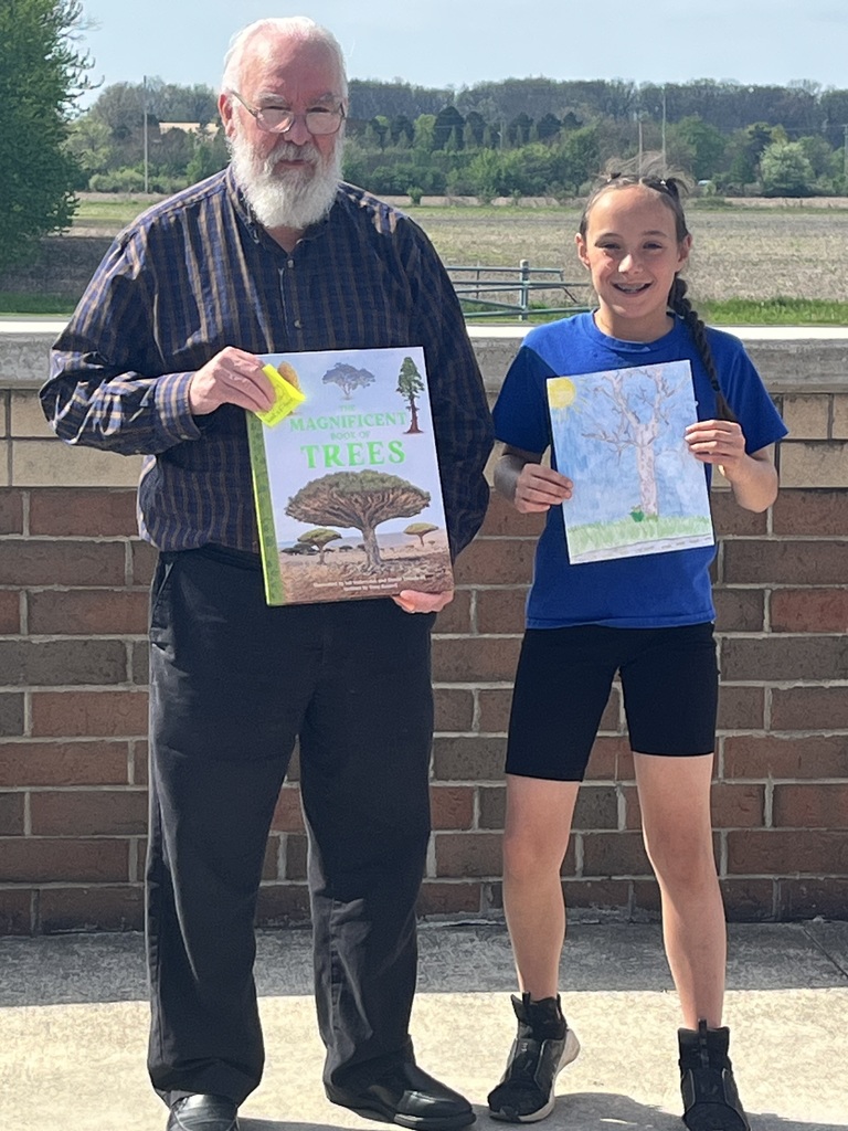 Mayor standing with student receiving book as prize outside on the patio