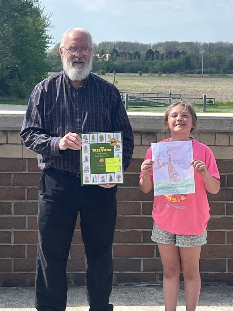 Mayor standing with student receiving book as prize outside on the patio