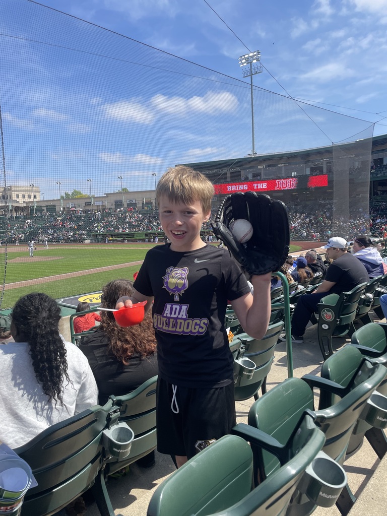 Student catching a baseball in a baseball glove in a stadium 