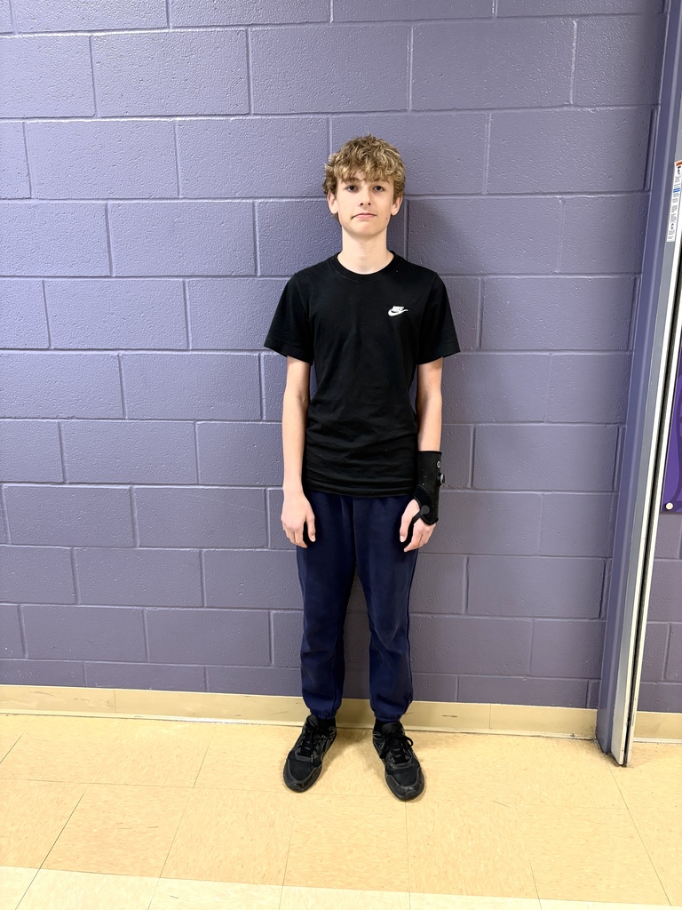 Student in black t-shirt standing in front of purple wall