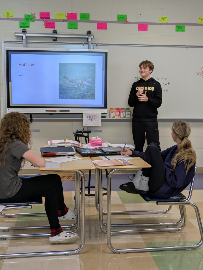 Student standing in front of a class teaching the ASL term for Habbitat