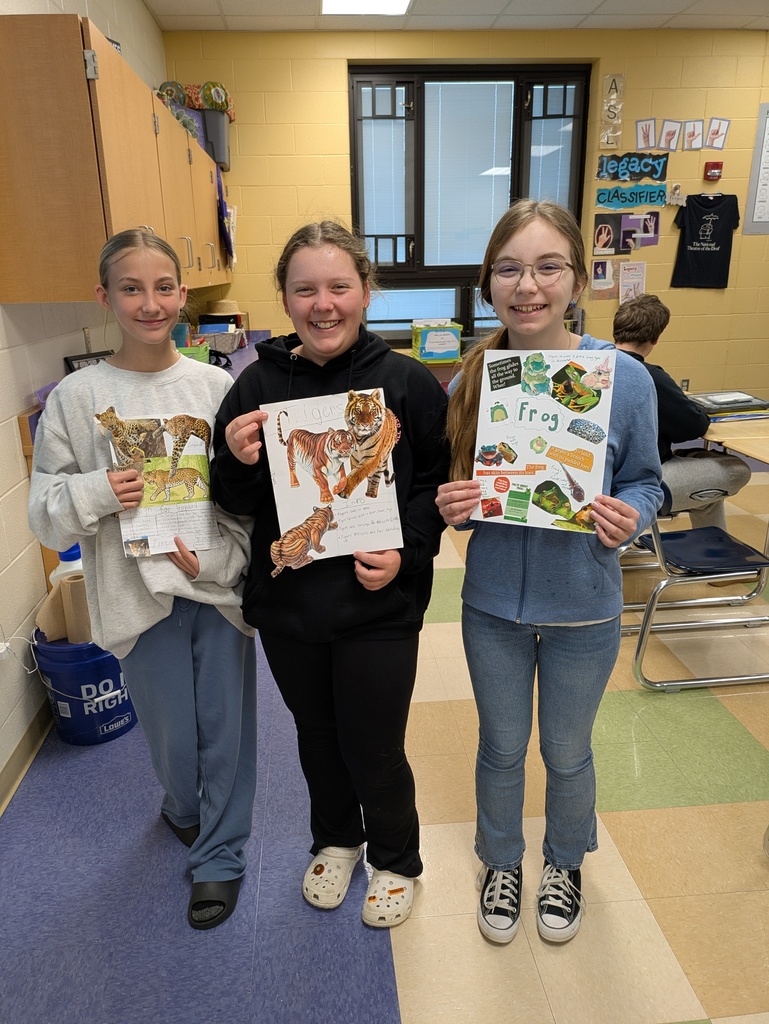 Three students holding displays if animal facts 