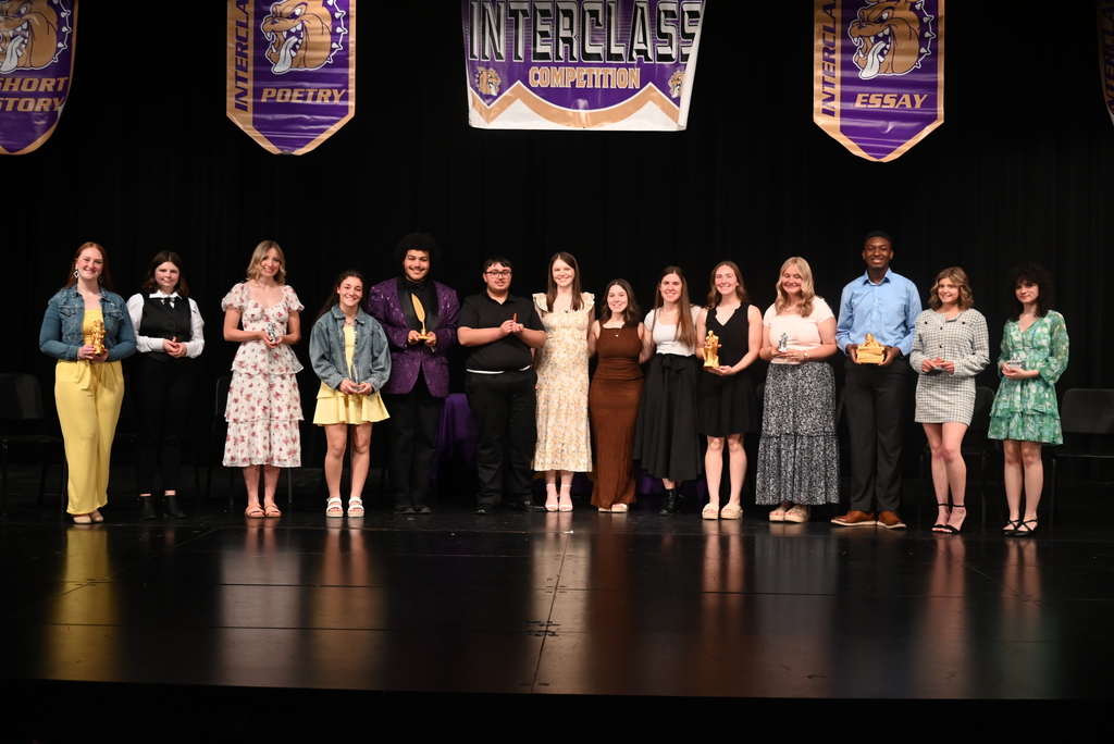 students standing in front of black background holding trophies