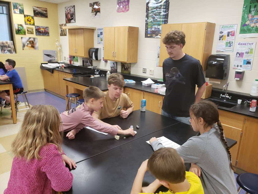 3rd grade students sitting at lab tables learning from high school students