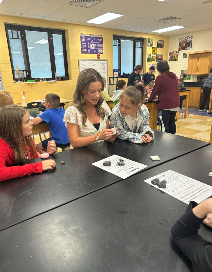 3rd grade students sitting at lab tables learning from high school students