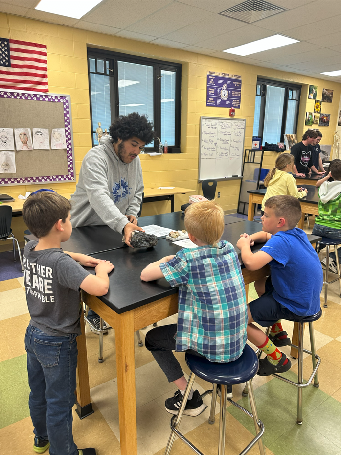3rd grade students sitting at lab tables learning from high school students