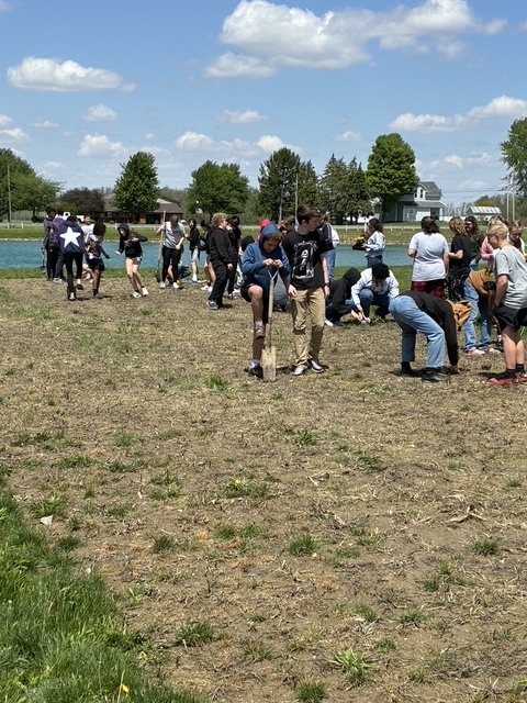 Students walking in the dirt planting seeds