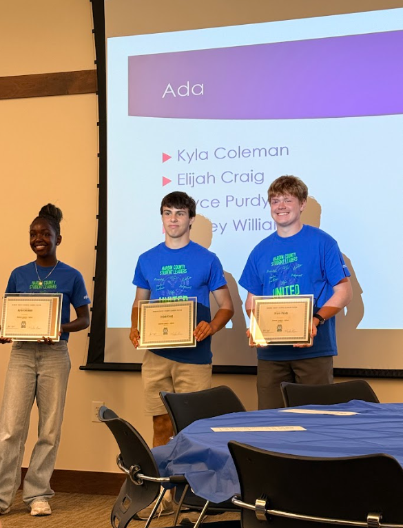 Three students standing in front of a presentation holding certificates
