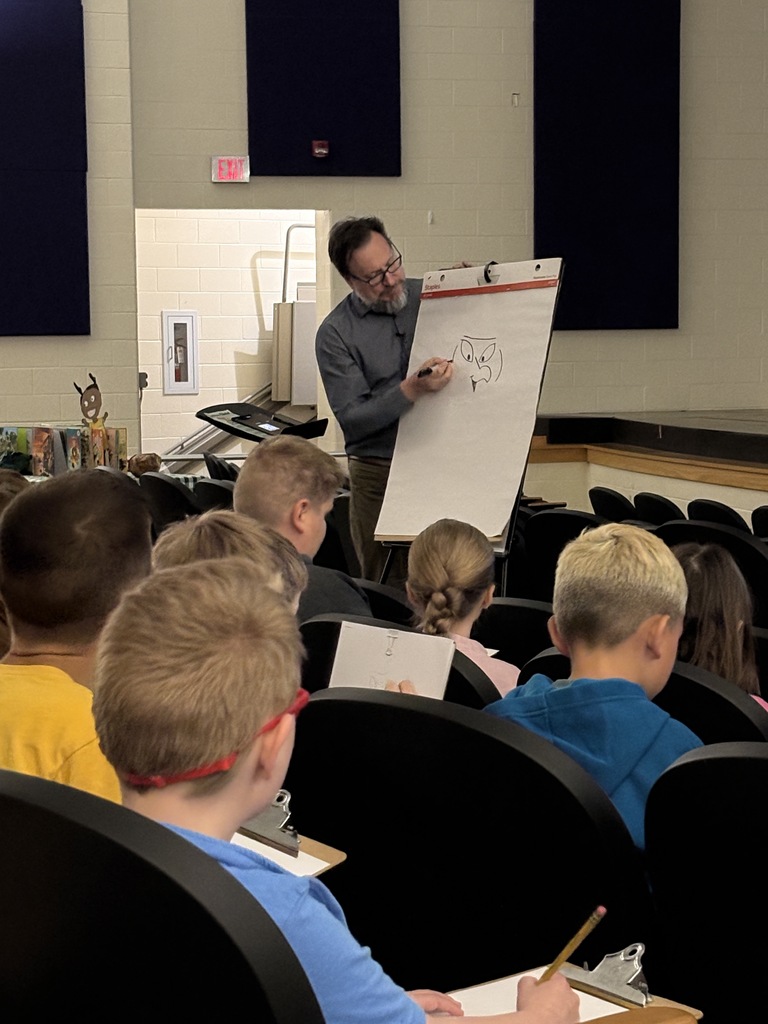 Man drawing on a large white notepad standing in front of students 