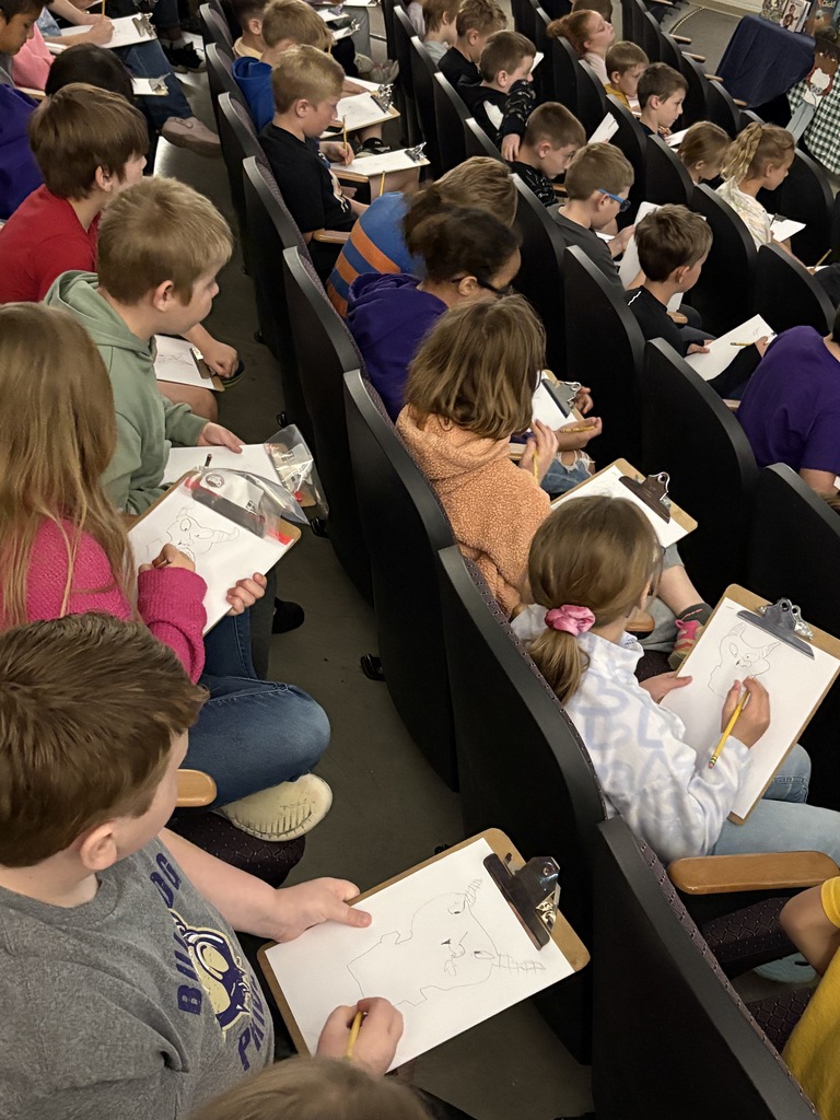 Students drawing on clip boards while seated