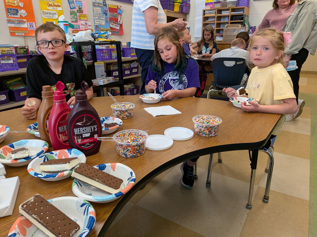 First grade students sitting around a table eating ice cream