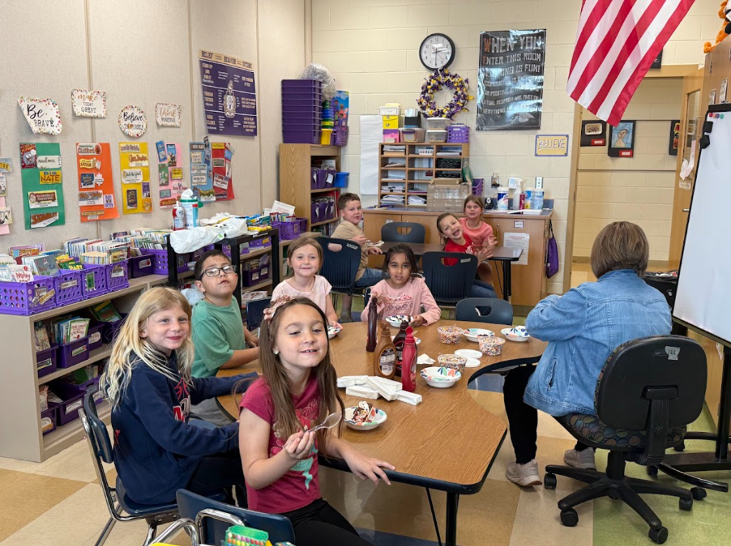 First grade students sitting around a table eating ice cream