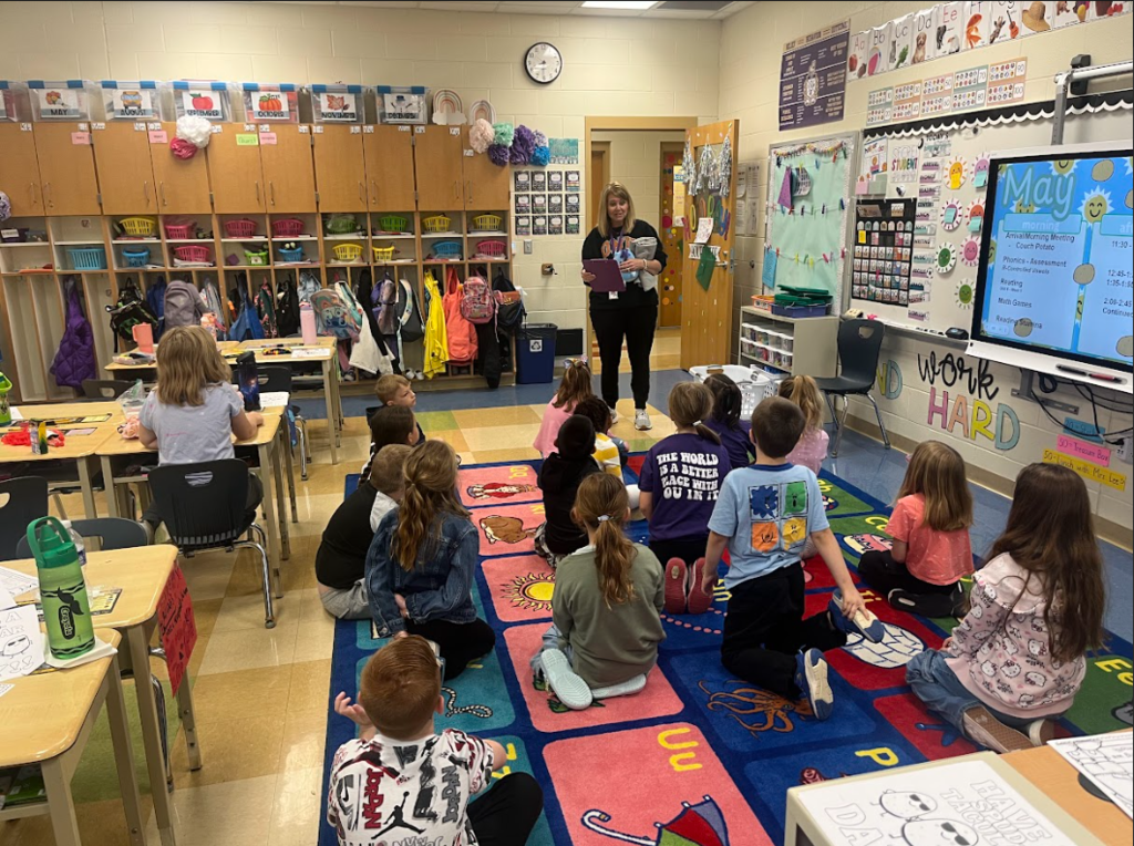 Adult speaking to students seating on a carpet