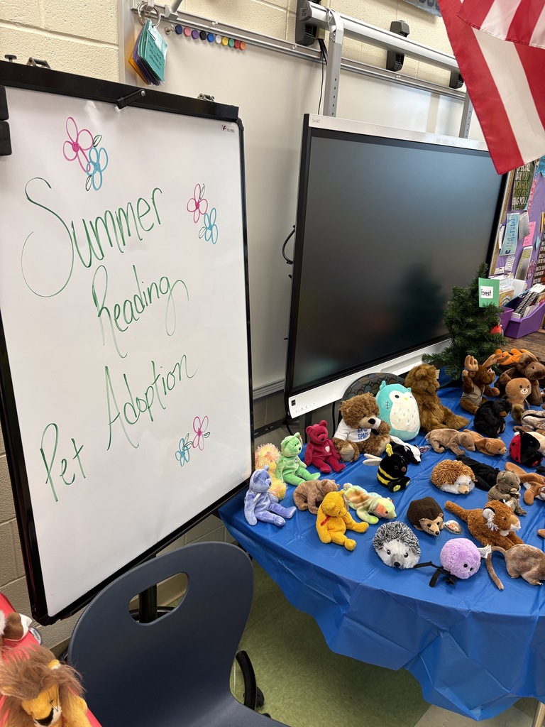 Table with blue cloth and stuffed animals with sign that reads: Summer Reading Pet Adoption