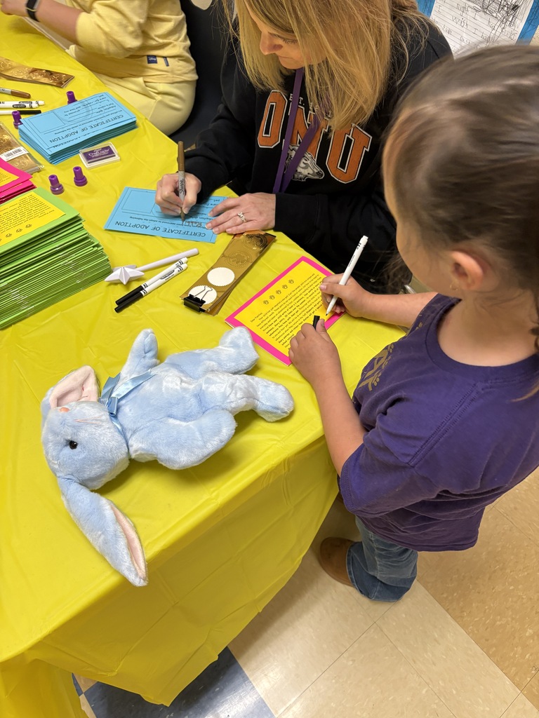Students standing at table with adult writing