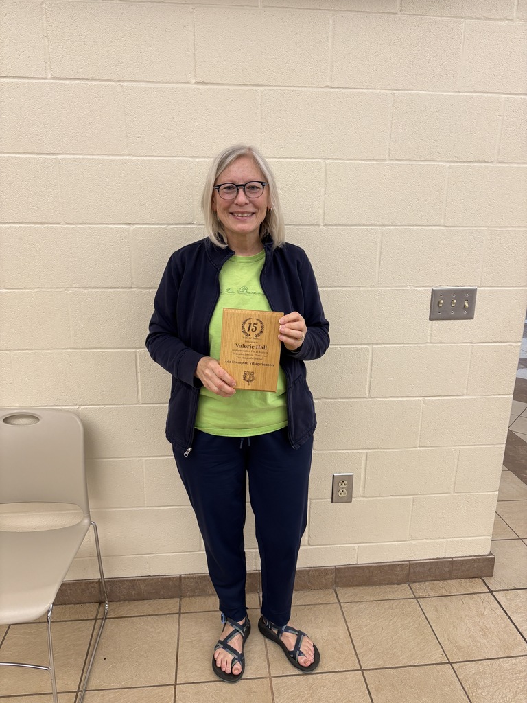Women standing holding a plaque with a green shirt and black jacket
