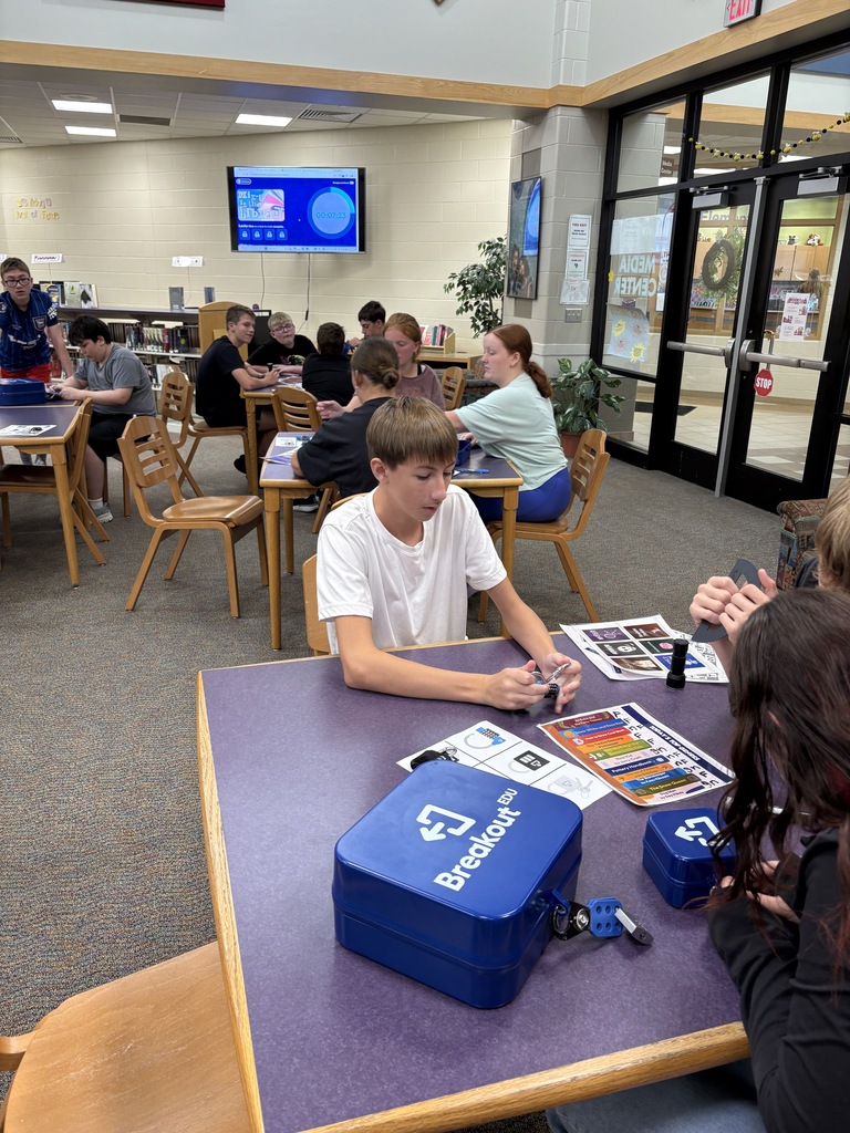 middle school students siting at a table with a blue box