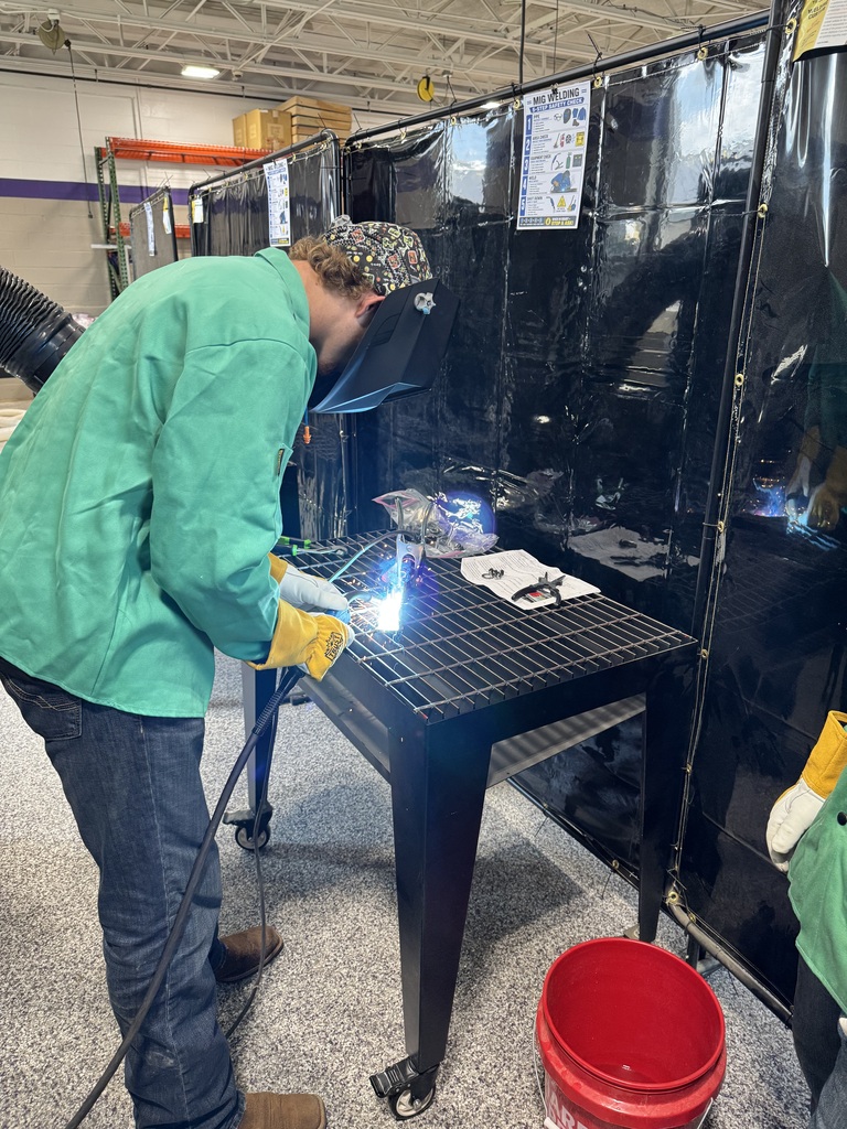 Student welding over a table