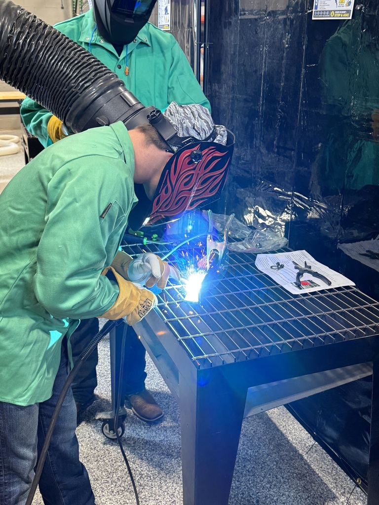 Student welding standing over a table. 