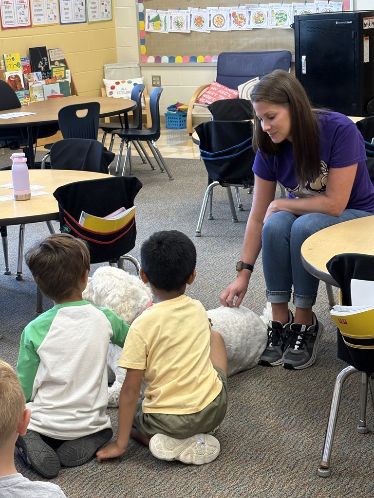Woman sitting in chair petting a dog with two young boys kneeled down to pet the dog
