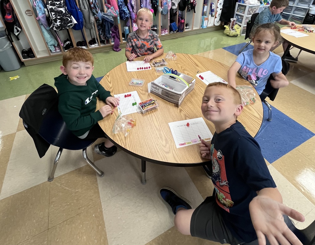 Four students sitting at a table with paper and water colors