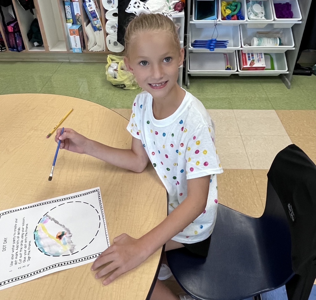 Four students sitting at a table with paper and water colors