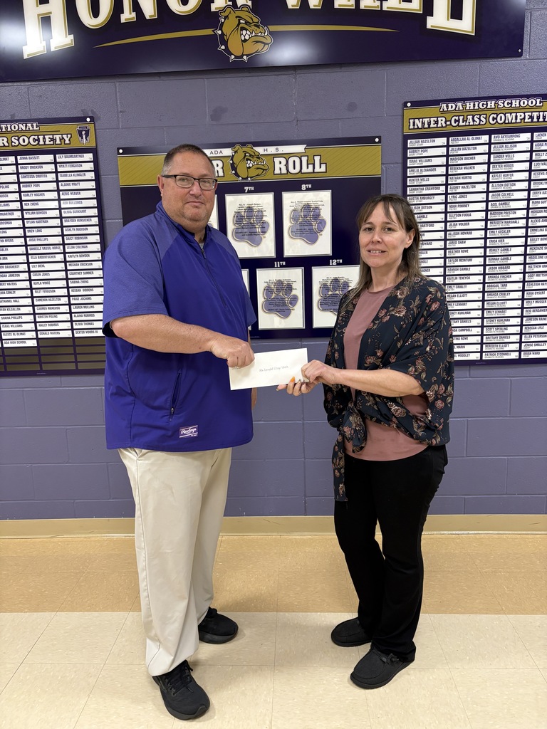Two people holding a check in front of a purple wall