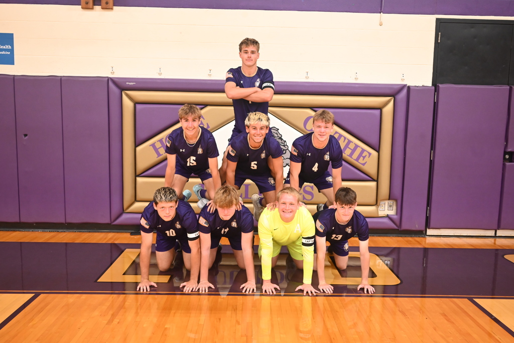 8 male student soccer players kneeling and standing in a pyramid shape