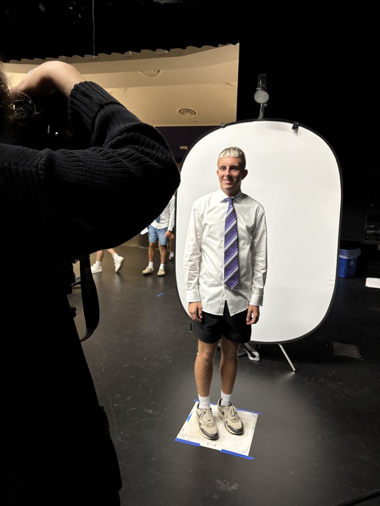 male student in white shirt standing in front of white background