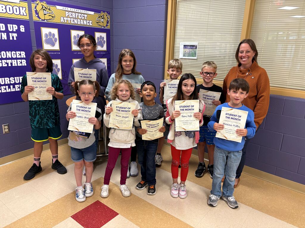Ten students standing holding certificates with one adult tot he right